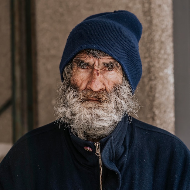 Vista frontal del hombre sin hogar con barba al aire libre