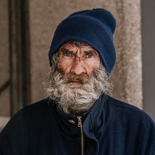 Vista frontal del hombre sin hogar con barba al aire libre