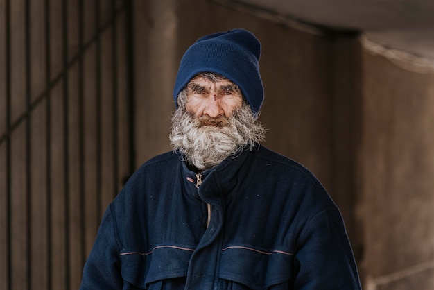 Vista frontal del hombre sin hogar barbudo en la calle