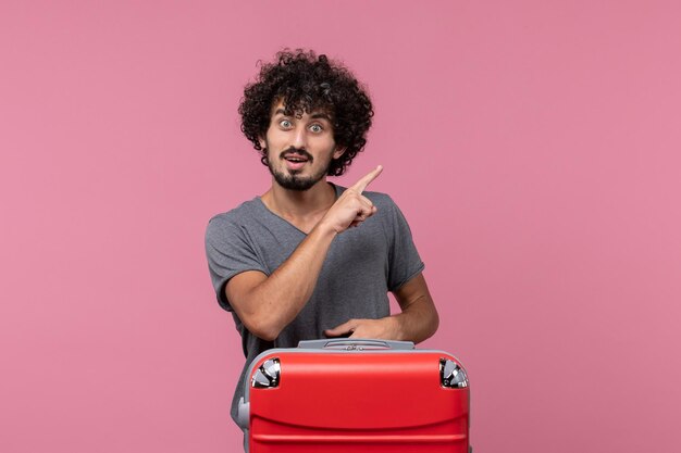 Vista frontal del hombre joven con bolsa roja apuntando al espacio rosa