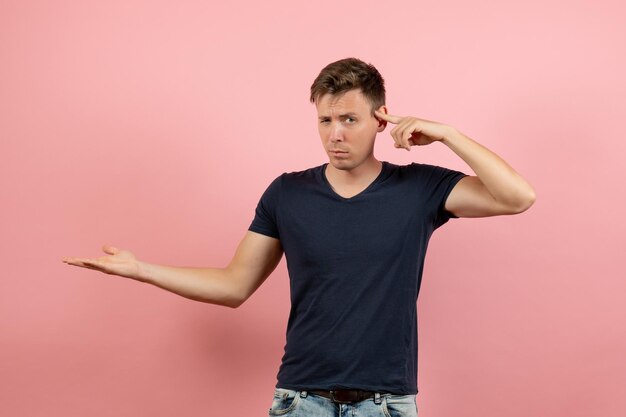 Vista frontal del hombre joven en camisa azul oscuro posando sobre fondo rosa