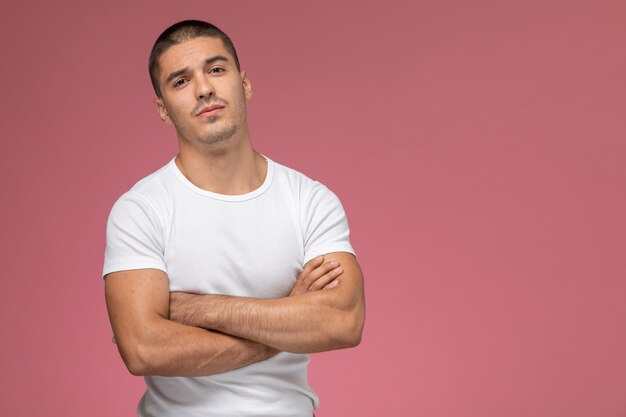 Vista frontal hombre joven en camisa blanca posando sobre el fondo rosa