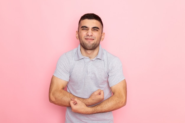 Foto gratuita vista frontal del hombre joven en camisa gris flexionando en rosa