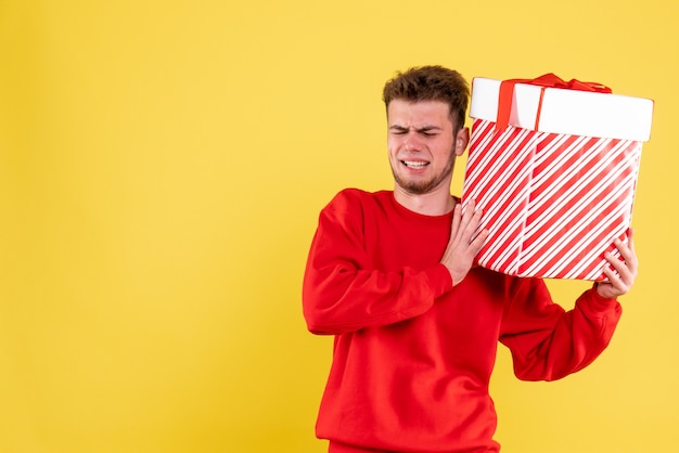 Vista frontal del hombre joven en camisa roja con regalo de Navidad