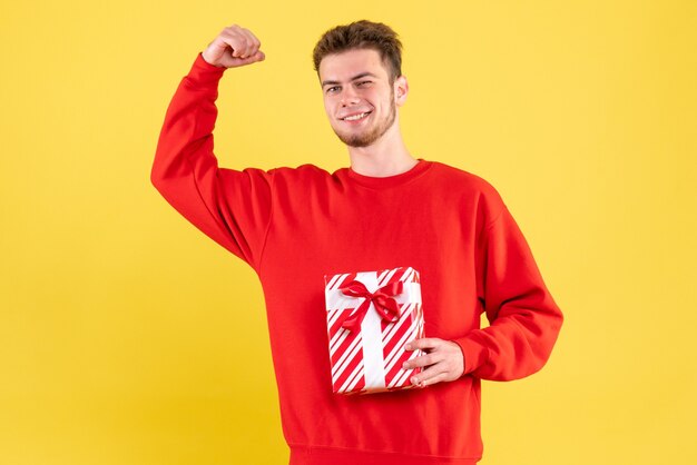 Vista frontal del hombre joven en camisa roja con regalo de Navidad