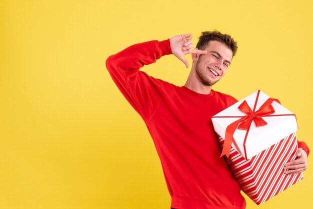 Vista frontal del hombre joven en camisa roja con regalo de Navidad