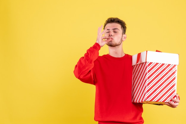 Vista frontal del hombre joven en camisa roja con regalo de Navidad