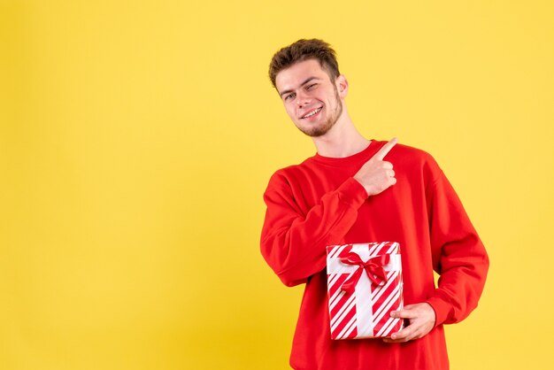 Vista frontal del hombre joven en camisa roja con regalo de Navidad