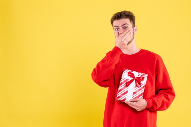 Vista frontal del hombre joven en camisa roja con regalo de Navidad