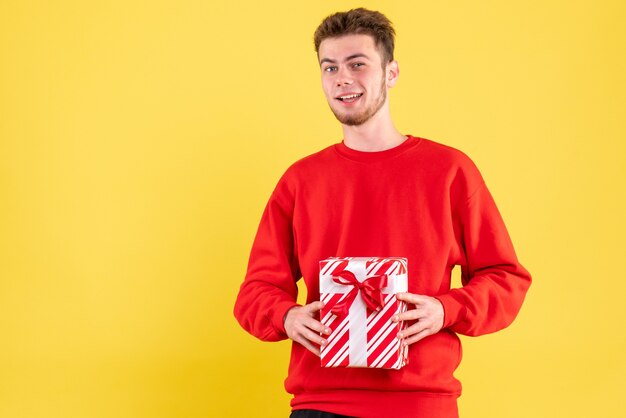 Vista frontal del hombre joven en camisa roja con regalo de Navidad