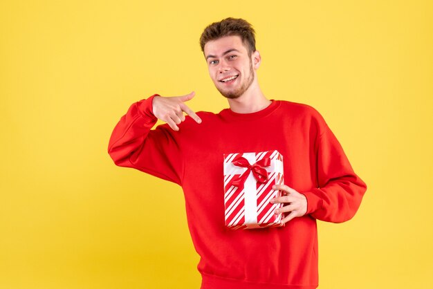 Vista frontal del hombre joven en camisa roja con regalo de Navidad