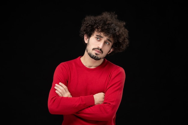Vista frontal del hombre joven en camisa roja sobre pared negra
