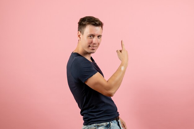 Vista frontal hombre joven en camiseta azul posando sobre el fondo rosa hombre modelo emoción color masculino