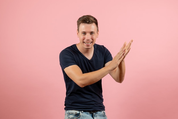 Vista frontal hombre joven en camiseta azul posando sobre el fondo rosa hombre modelo emoción color masculino