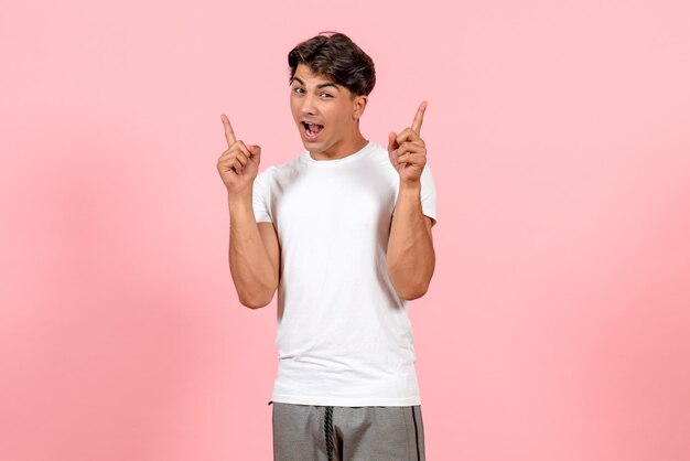 Vista frontal hombre joven en camiseta blanca en color rosa piso modelo emoción masculina