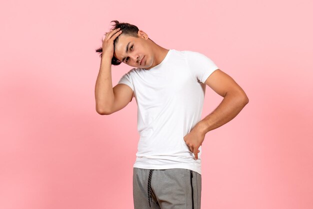 Vista frontal del hombre joven en camiseta blanca sobre fondo rosa claro