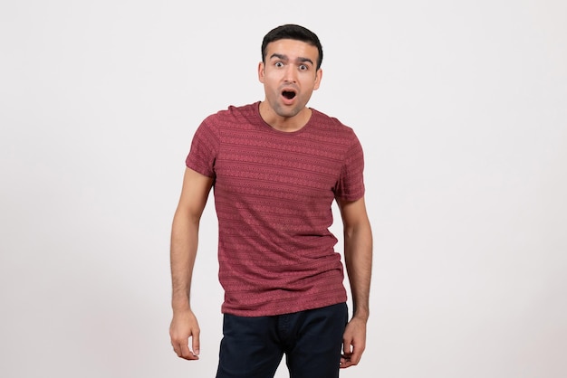 Foto gratuita vista frontal del hombre joven en camiseta de color rojo oscuro de pie sobre fondo blanco.