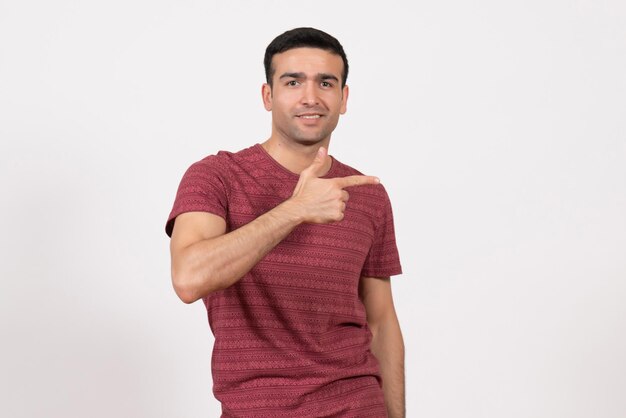 Vista frontal del hombre joven en camiseta de color rojo oscuro posando sobre fondo blanco claro