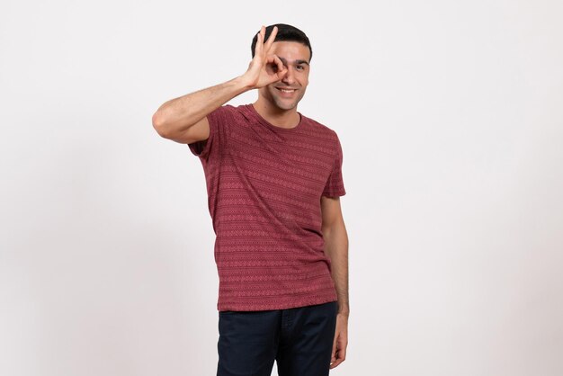 Vista frontal del hombre joven en camiseta de color rojo oscuro posando sobre fondo blanco claro