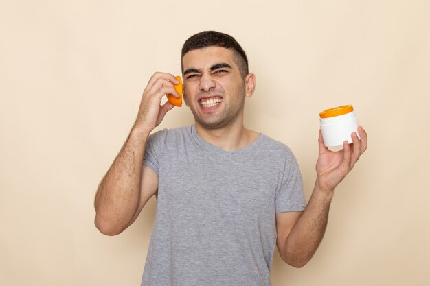 Vista frontal del hombre joven en camiseta gris con rodajas de naranja sobre beige