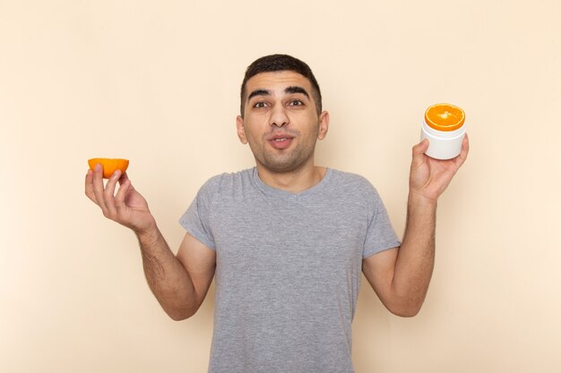 Vista frontal del hombre joven en camiseta gris con rondas naranjas sobre beige