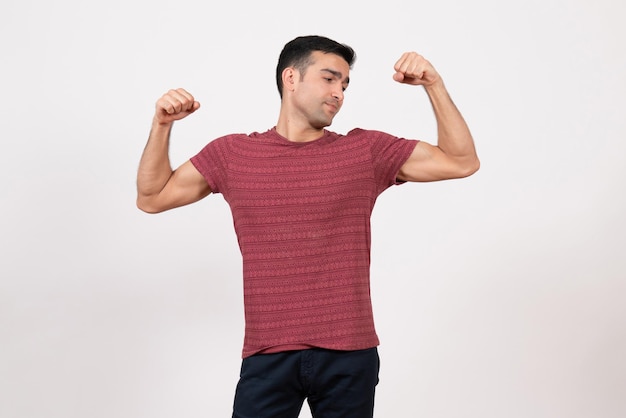 Vista frontal del hombre joven en camiseta posando y flexionando sobre fondo blanco.