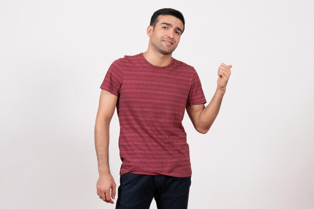 Vista frontal del hombre joven en camiseta posando y sonriendo sobre fondo blanco.