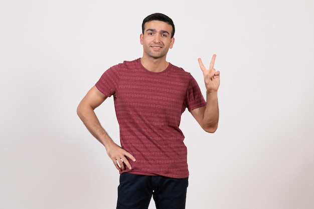 Vista frontal del hombre joven en camiseta posando y sonriendo sobre fondo blanco.