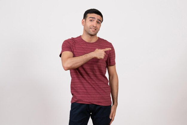 Vista frontal del hombre joven en camiseta posando y sonriendo sobre fondo blanco.