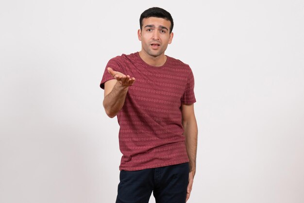 Vista frontal del hombre joven en camiseta roja oscura posando sobre fondo blanco.