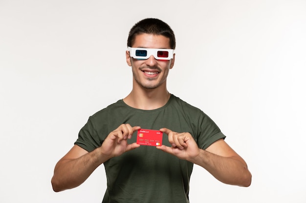 Vista frontal del hombre joven en camiseta verde con tarjeta bancaria en gafas de sol d en película de pared blanca cine solitario