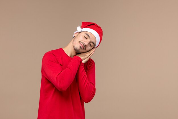 Vista frontal hombre joven cansado y tratando de dormir sobre fondo marrón emoción vacaciones de navidad