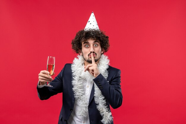 Vista frontal del hombre joven celebrando el año nuevo que viene en la pared roja Navidad humana de vacaciones