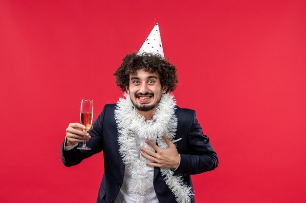 Vista frontal del hombre joven celebrando el año nuevo que viene en la pared roja Navidad humana de vacaciones