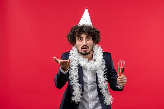 Vista frontal del hombre joven celebrando las vacaciones de año nuevo en una pared roja color parte humana