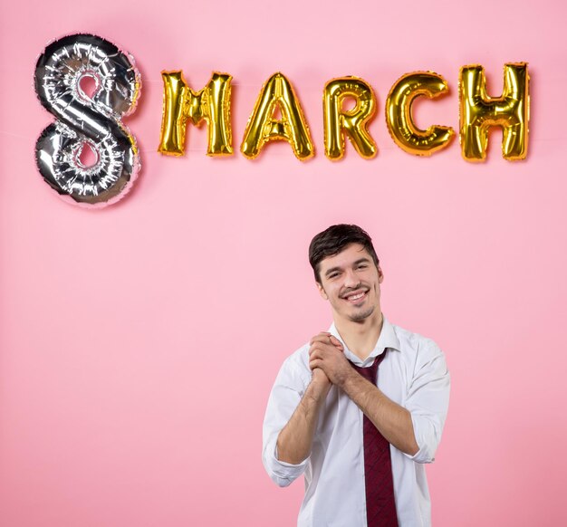 Vista frontal hombre joven con decoración de marzo sobre fondo rosa color matrimonio femenino día de la mujer hombre fiesta igualdad presente