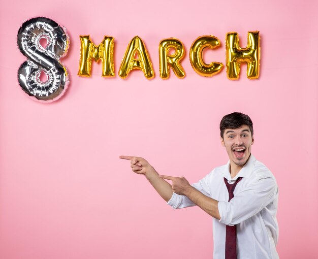 Vista frontal hombre joven con decoración de marzo sobre fondo rosa matrimonio fiesta igualdad femenino día de la mujer presente colores hombre