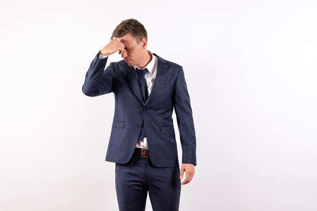 Vista frontal del hombre joven en elegante traje clásico con dolor de cabeza sobre fondo blanco claro