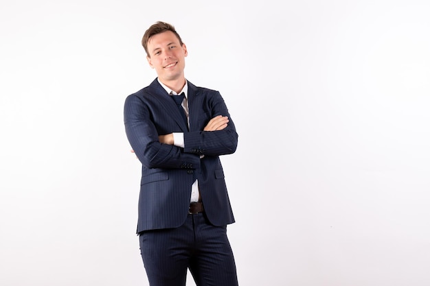 Foto gratuita vista frontal del hombre joven en elegante traje clásico sonriendo y posando sobre fondo blanco.