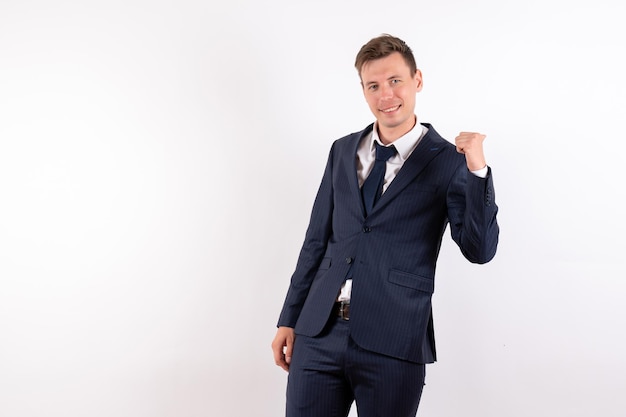 Vista frontal del hombre joven en elegante traje clásico sonriendo sobre fondo blanco.