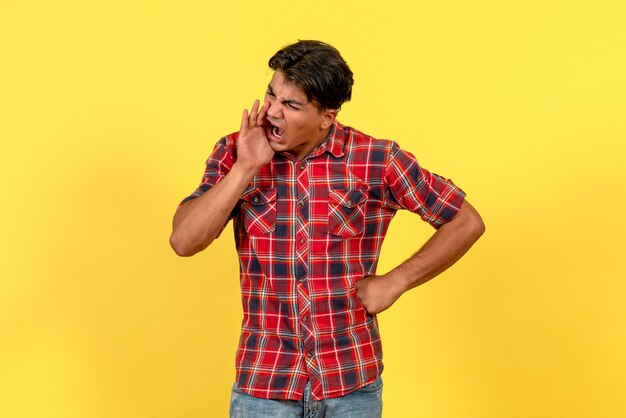 Vista frontal hombre joven llamando a alguien sobre fondo amarillo color de modelo masculino