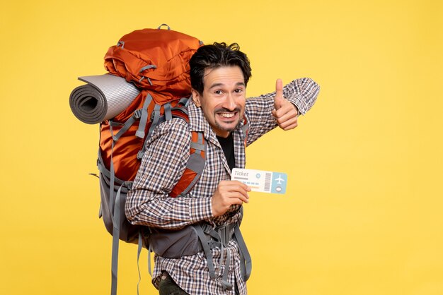 Vista frontal del hombre joven con mochila con boleto en amarillo