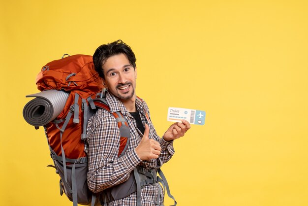 Vista frontal del hombre joven con mochila con boleto en amarillo