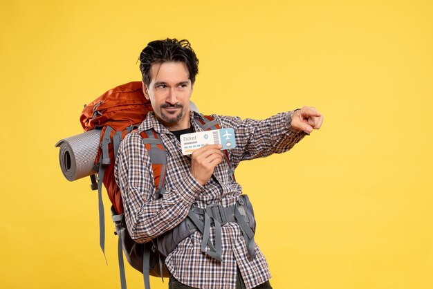 Vista frontal del hombre joven con mochila con boleto en amarillo