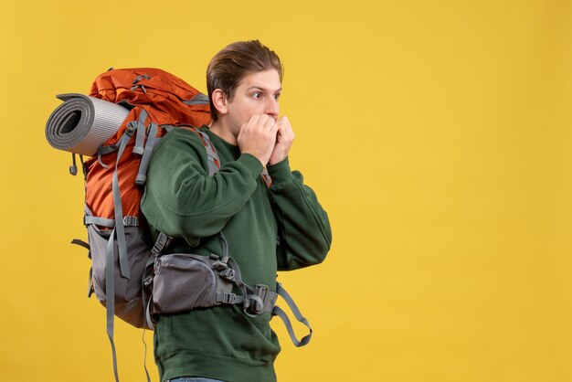 Vista frontal del hombre joven con mochila preparándose para el senderismo asustado
