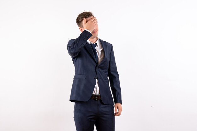 Vista frontal hombre joven que cubre su rostro en traje clásico estricto sobre fondo blanco modelo de moda emociones de negocios masculino