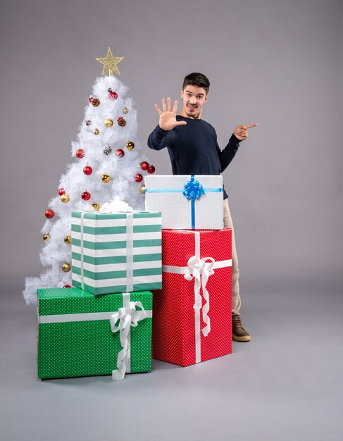 Vista frontal del hombre joven con regalos de Navidad en una luz