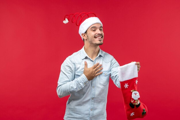 Vista frontal del hombre joven sosteniendo un calcetín de Navidad, vacaciones de Navidad