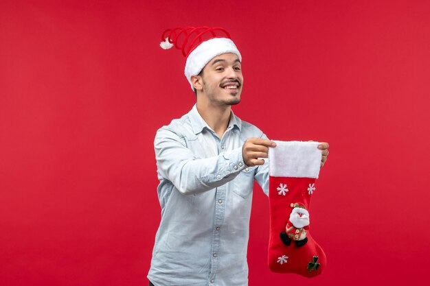 Vista frontal del hombre joven sosteniendo un calcetín de Navidad, vacaciones de Navidad