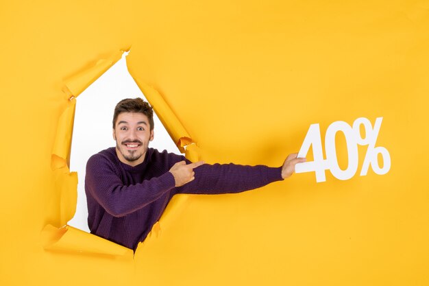 Vista frontal hombre joven sosteniendo la escritura sobre fondo amarillo compras regalo navideño foto color